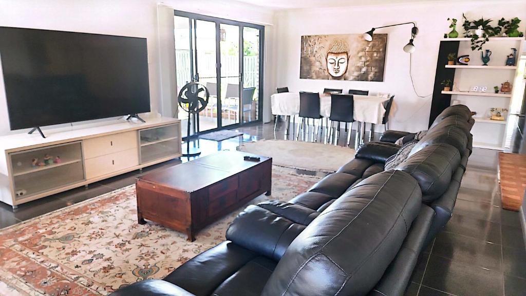 黄金海岸Kumera Home的客厅配有真皮沙发和平面电视