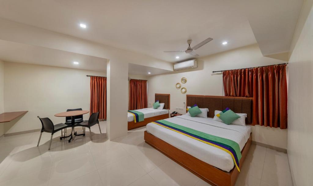 哥印拜陀Treebo Trend Sam Residency的酒店客房设有两张床和一张桌子。