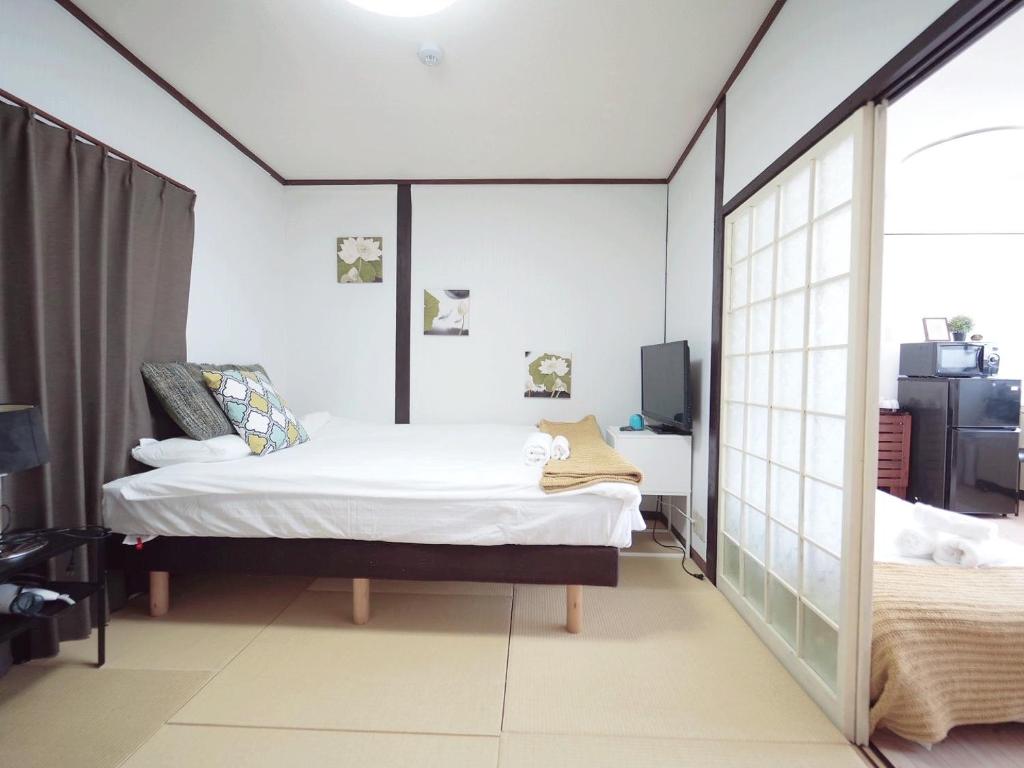 大阪Nippori Osaka Nishi-Tengachaya Guesthouse西天下茶屋アパートメント的一间卧室配有一张床和镜子