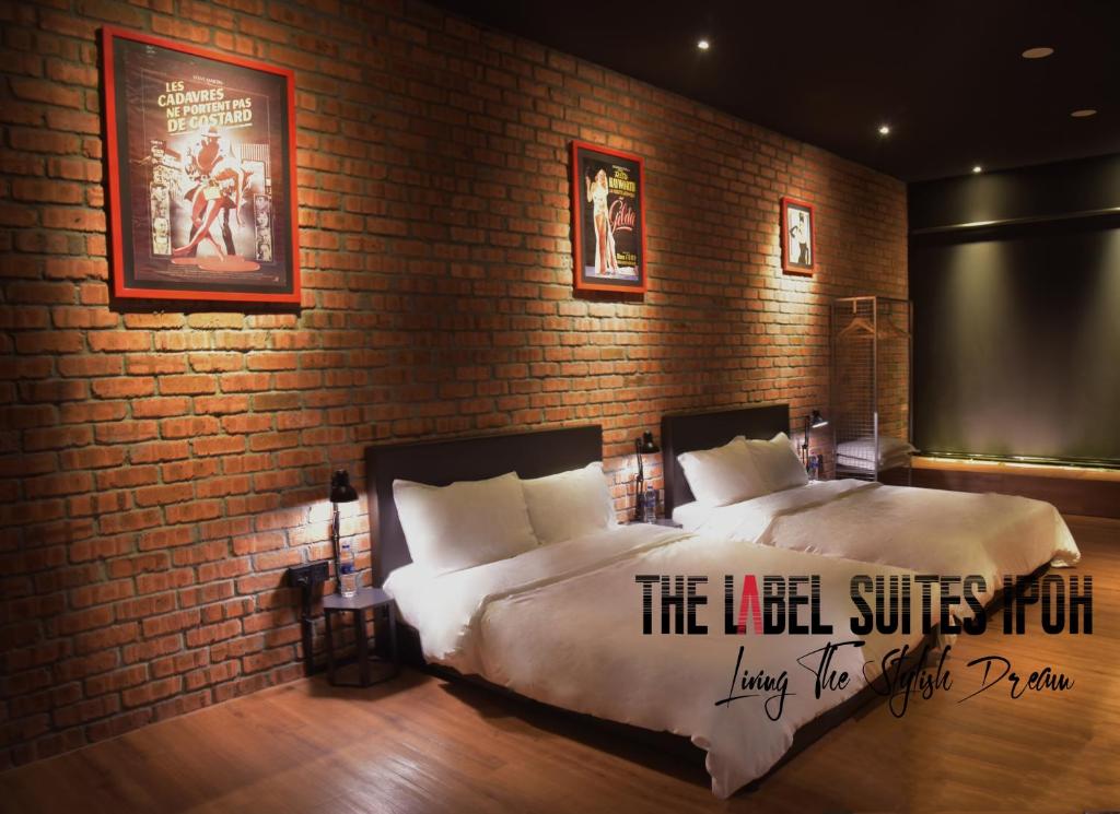 怡保The Label Suites Ipoh的一间卧室设有一张床和砖墙