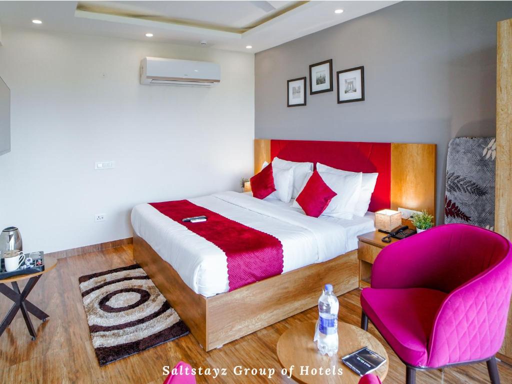 古尔冈Saltstayz Hotel Huda City Centre的一间卧室配有一张大床和一张粉红色的椅子