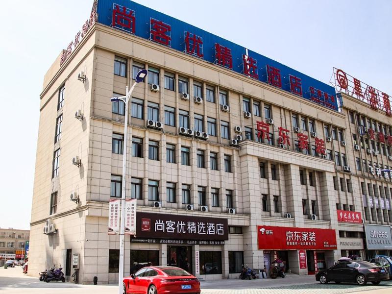 明光尚客优精选滁州明光星光商贸城酒店的一座大型建筑,前面有汽车停放