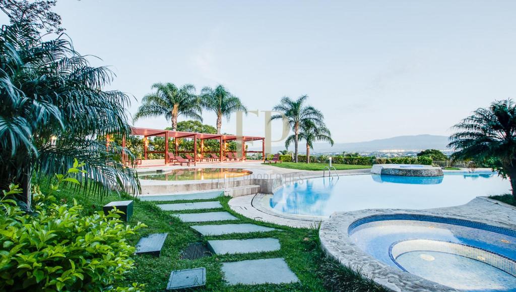 圣安娜CR MARIPOSA RENTALS Comfortable penthouse, AC, pool, gym, tennis的一个带游泳池和棕榈树的度假村