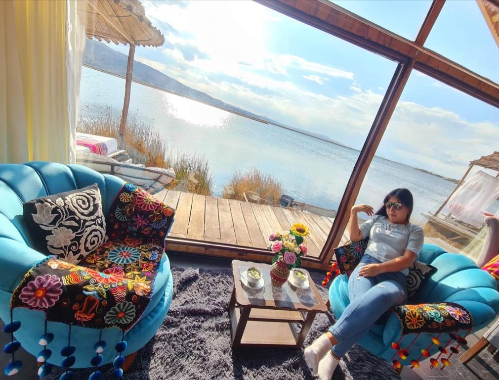 普诺Uros Walysuma Titicaca Lodge的坐在椅子上的女人,坐在一个水景房间里