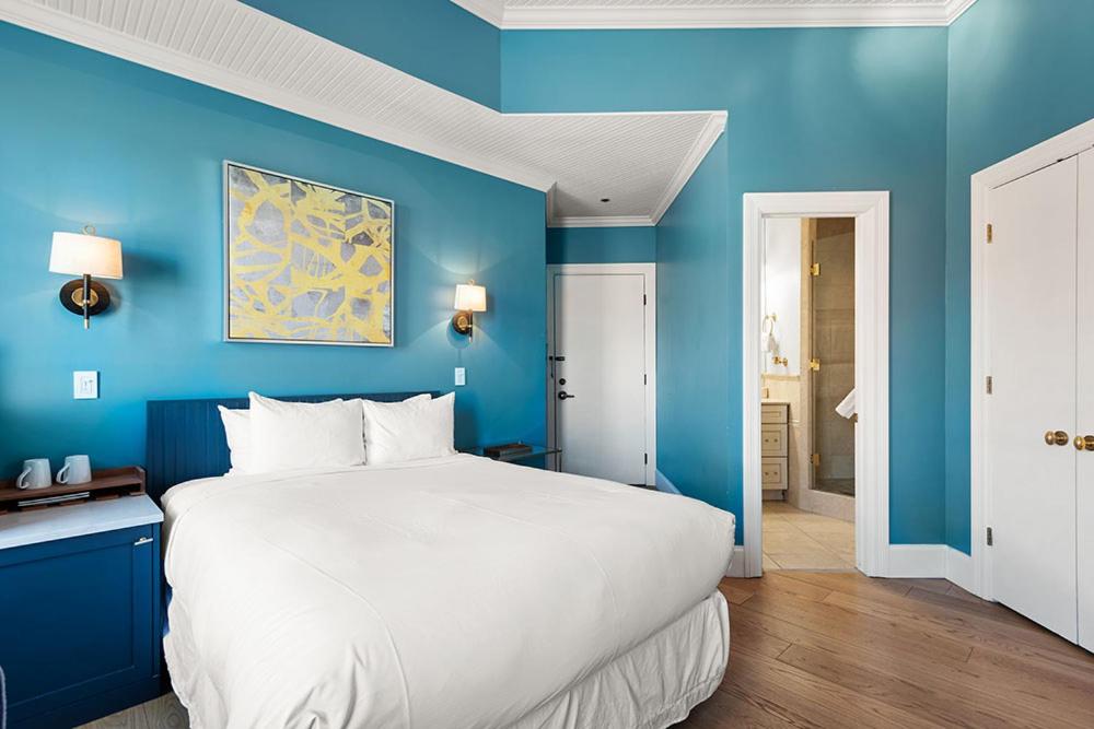 阿斯潘Independence Square 205, Stylish Hotel Room with AC, Great Location in Aspen的卧室配有蓝色墙壁上的一张白色大床