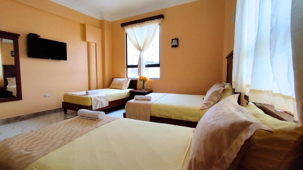 瓜亚基尔Hostal California Inn的酒店客房设有两张床和电视。