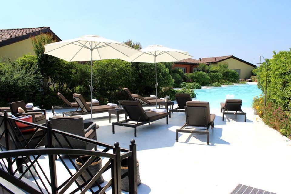 布鲁萨珀尔图周雅豪华公寓酒店的游泳池旁带椅子和遮阳伞的天井