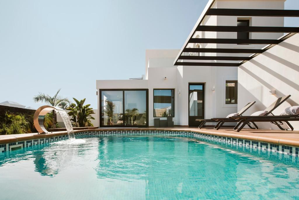 普拉亚布兰卡Villa Faro的一个带两把椅子的游泳池以及一座房子
