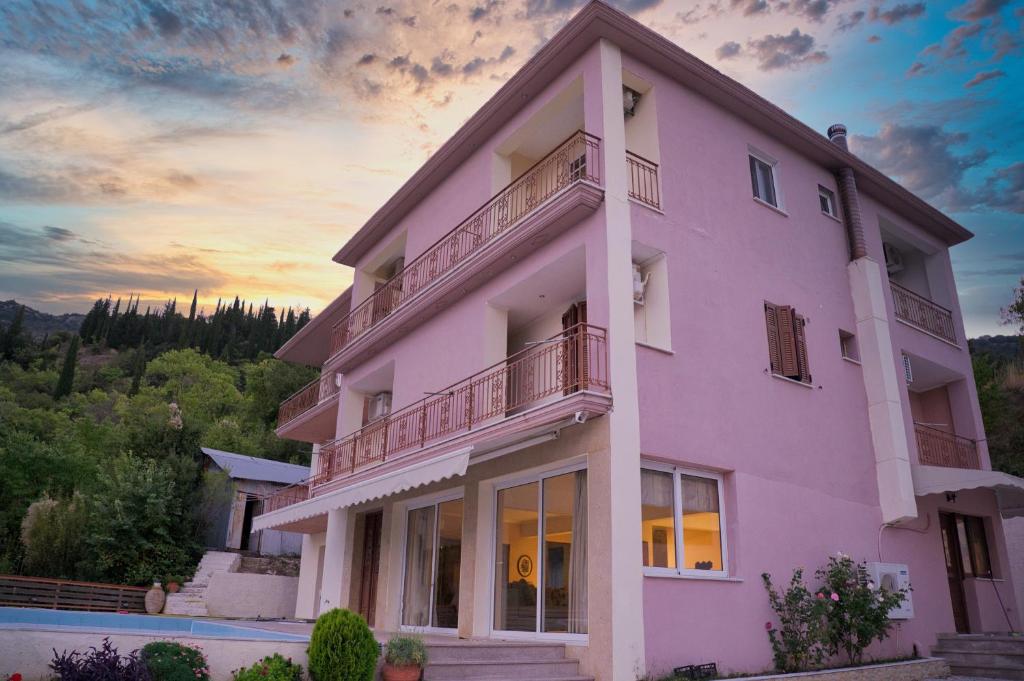 KariáPetronas Villa的粉红色的建筑,背景是日落