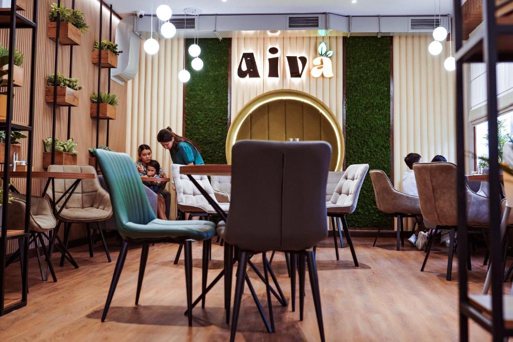 比什凯克Aiva Hostel的餐厅设有椅子,而客人则坐在桌子上