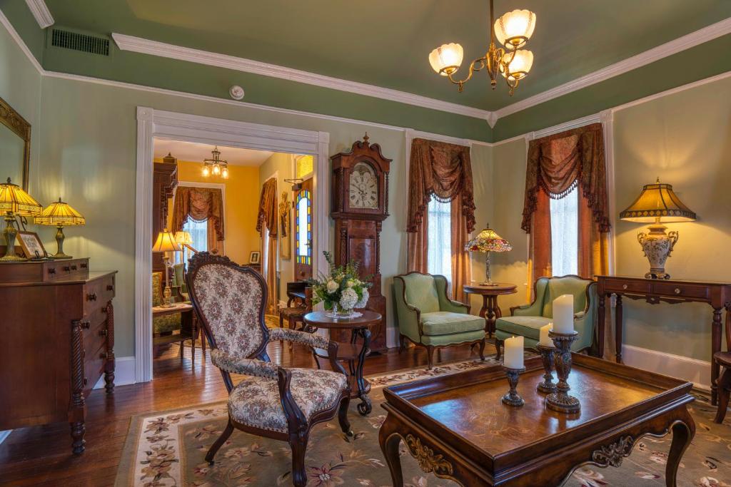 圣奥古斯丁Victorian House Bed and Breakfast的客厅配有桌椅和时钟