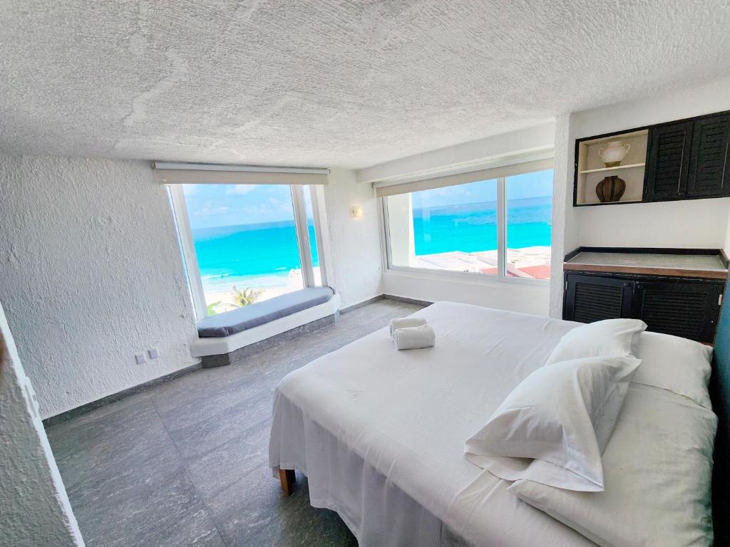坎昆酒店区罗德罗索利马尔海滩公寓的卧室设有白色床,享有海景