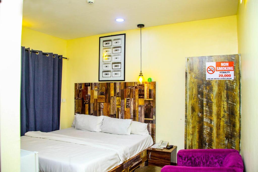 拉各斯ONTARIO SUITES的一间卧室配有一张床和一张紫色椅子