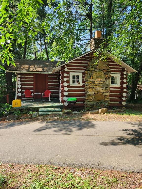 阿什维尔The Pines Cottages的小木屋前方设有红色椅子