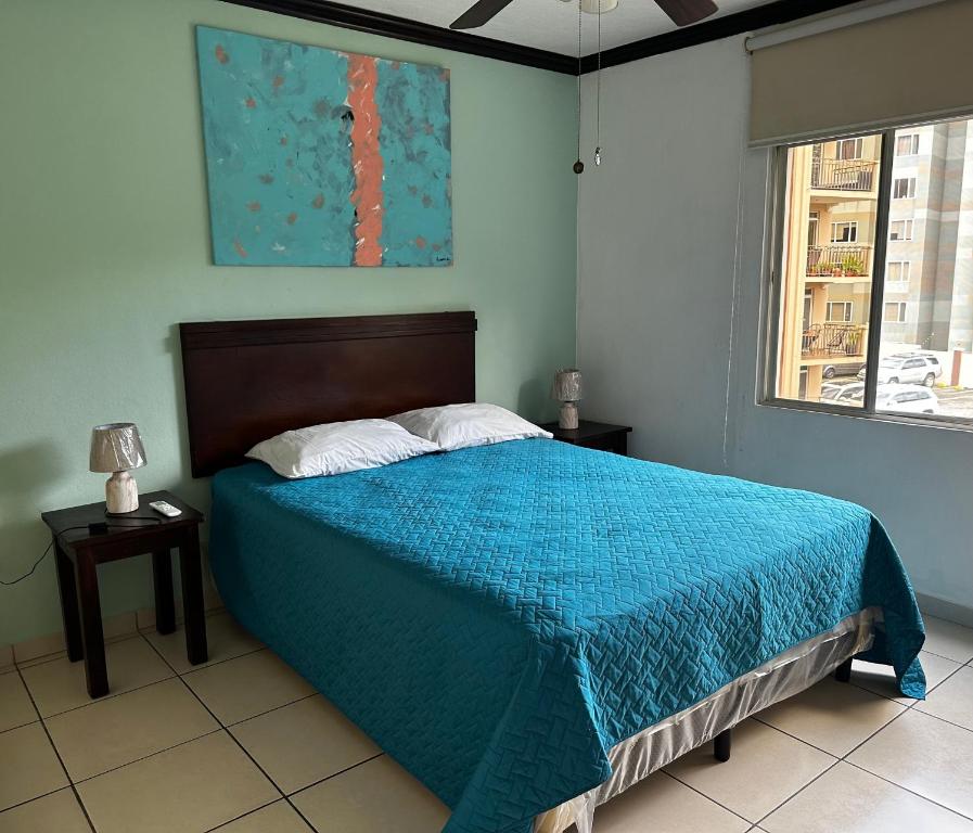 圣萨尔瓦多MonBlanc的一间卧室配有一张带蓝色毯子的床和窗户。