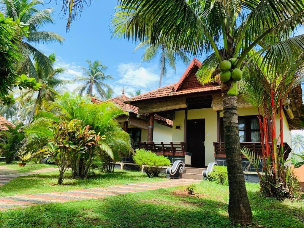 瓦尔卡拉Maadathil Cottages & Beach Resort的前面有棕榈树的房子