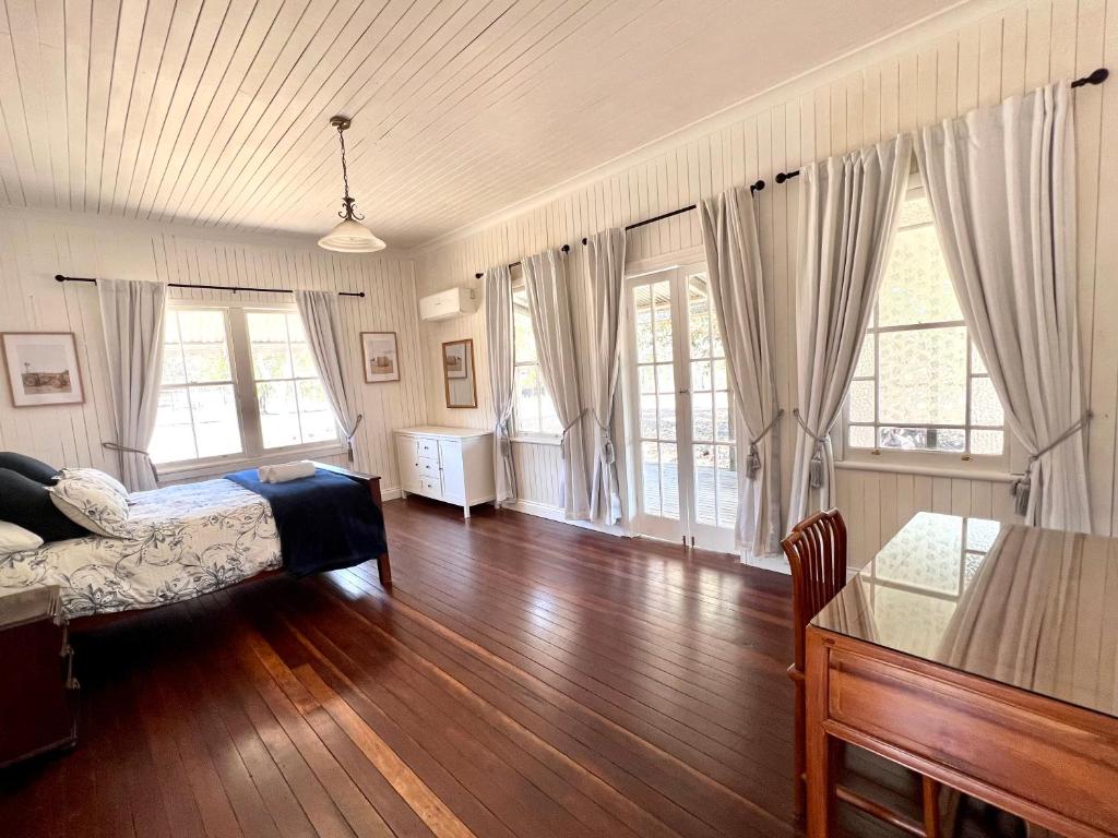 GrandchesterThe Cottage Farm Stay - Grandchester的卧室配有一张床、木地板和窗户。