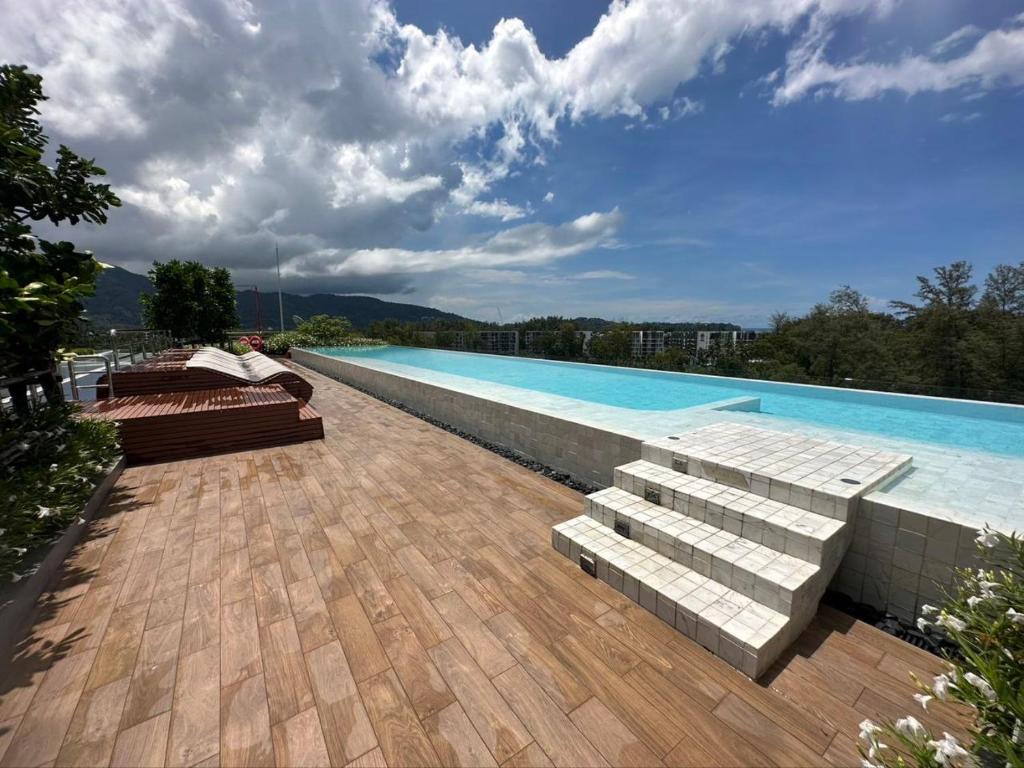 邦涛海滩Apartments in Skypark Laguna Bang Tao的木甲板旁带长椅的游泳池