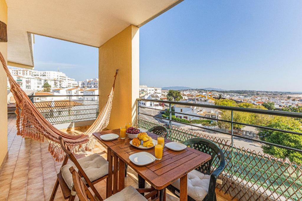拉戈斯Lagos Sea View by Algarve Golden Properties的阳台配有木桌、椅子和吊床。