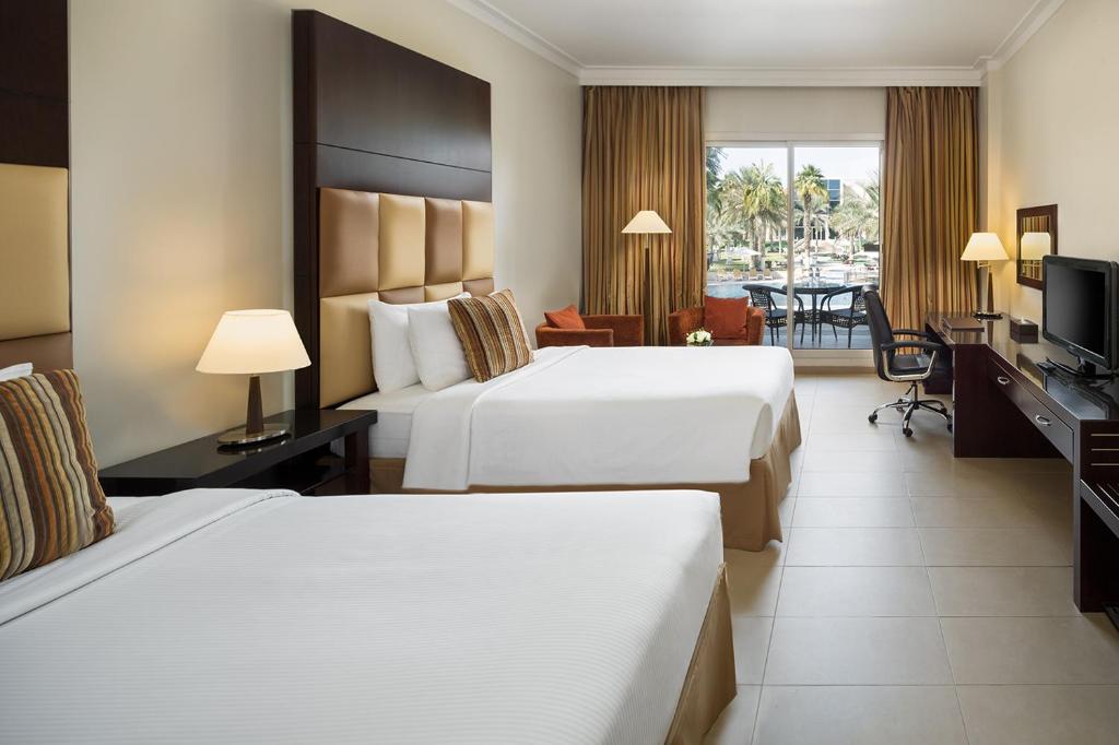 阿布扎比Metropolitan Al Mafraq Hotel的酒店客房设有两张床和电视。