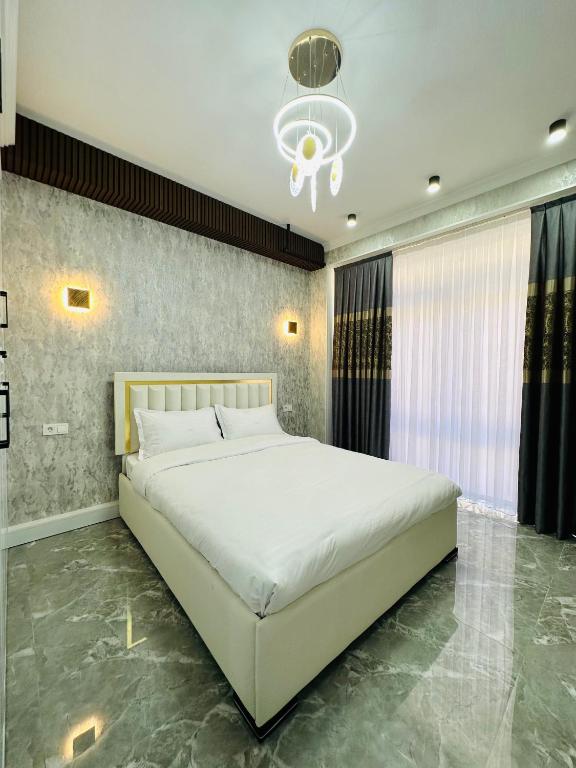 TürkistanKERUEN SARAY APARTMENTS 20/2的卧室配有一张白色大床和吊灯。