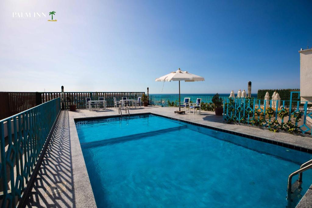 赫尔格达Palm Inn Suites Hotel的一个带遮阳伞的游泳池以及大海