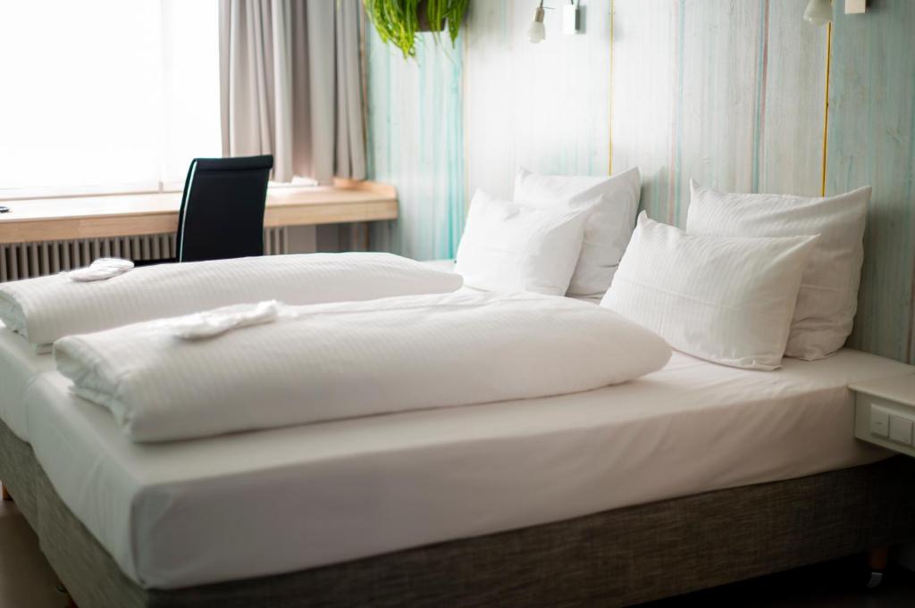 斯图加特阿巴理想酒店的一张带白色床单和枕头的床