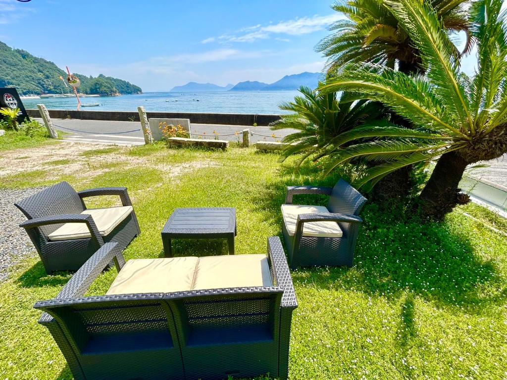 尾道市Beach Villa Tachibana的一群桌子和椅子,放在水边的草上