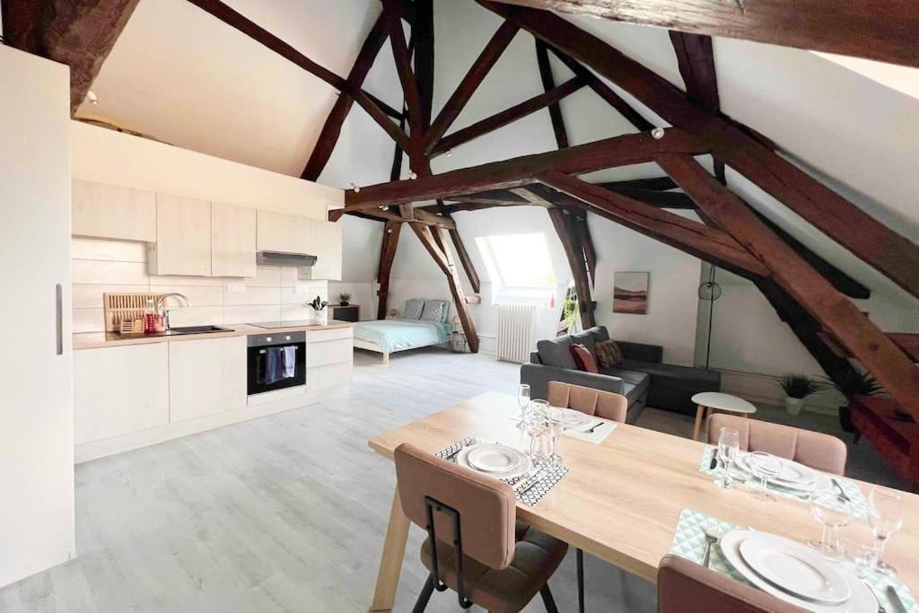 欧塞尔Charme plein cœur Auxerre - parking privé的厨房以及带木桌和椅子的客厅。