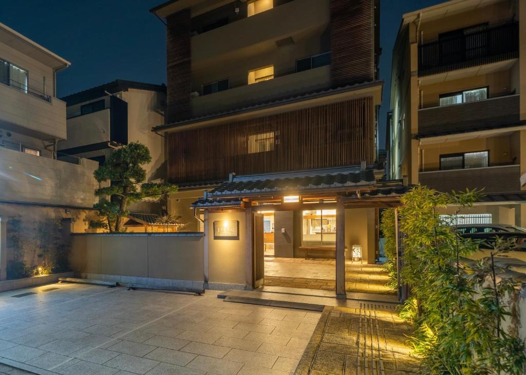 京都RESI STAY Jisco Hotel Kyoto Goshonishi的夜晚在建筑物前的庭院