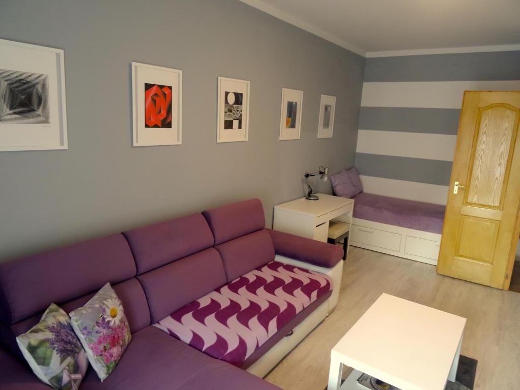 佩奇Árkád Apartman-Pécs的客厅配有紫色沙发和桌子