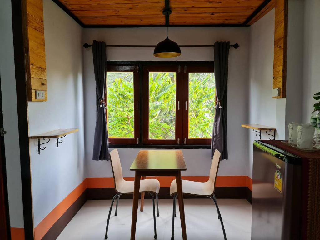 班柯木Mookboonchu Guesthouse ,Kohmook Trang的窗户间里的一张桌子和两把椅子