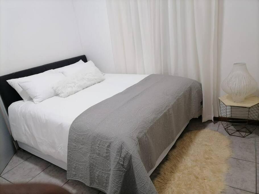 开普敦Two bedroom flatlet in Panorama的一间卧室配有一张白色的床和黑色床头板