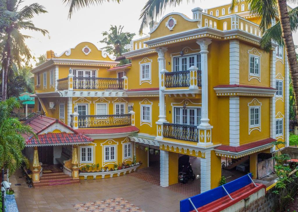 马焦茹达The Royal Oasis Goa的大型黄色建筑,设有白色窗户和阳台