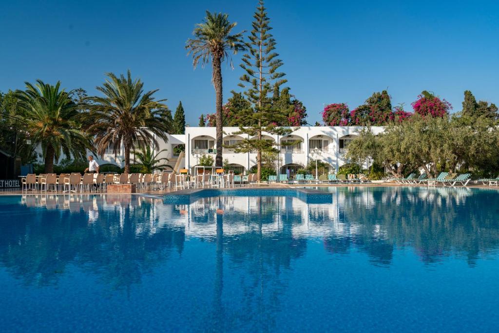 哈马马特Le Hammamet Hotel & SPA的一个带椅子和棕榈树的大型游泳池