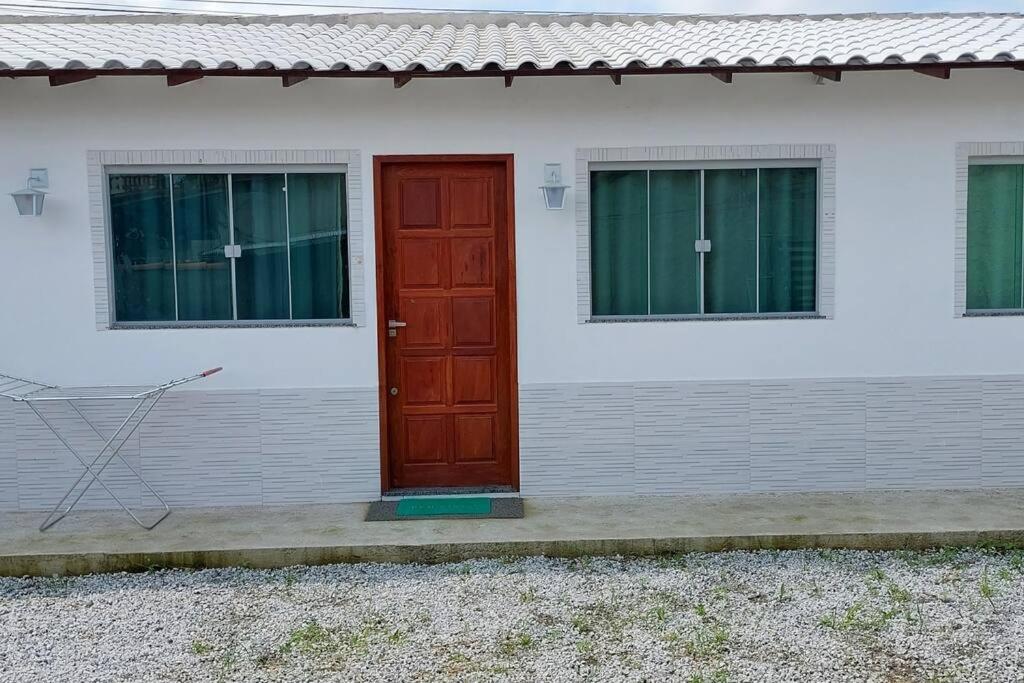 阿拉鲁阿马Casa tranquila 2 Q, bem localizada, ar opcional wifi grátis.的白色房子边的红色门
