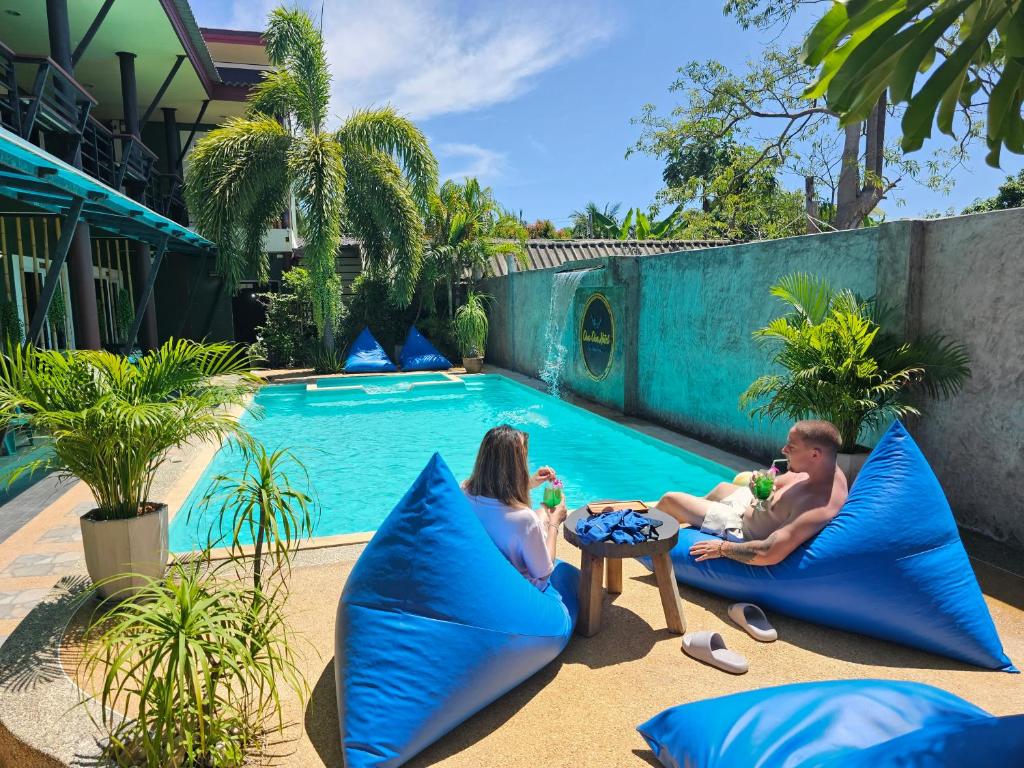 高兰Cha-Cha Hotel的坐在游泳池旁的枕头上的家庭
