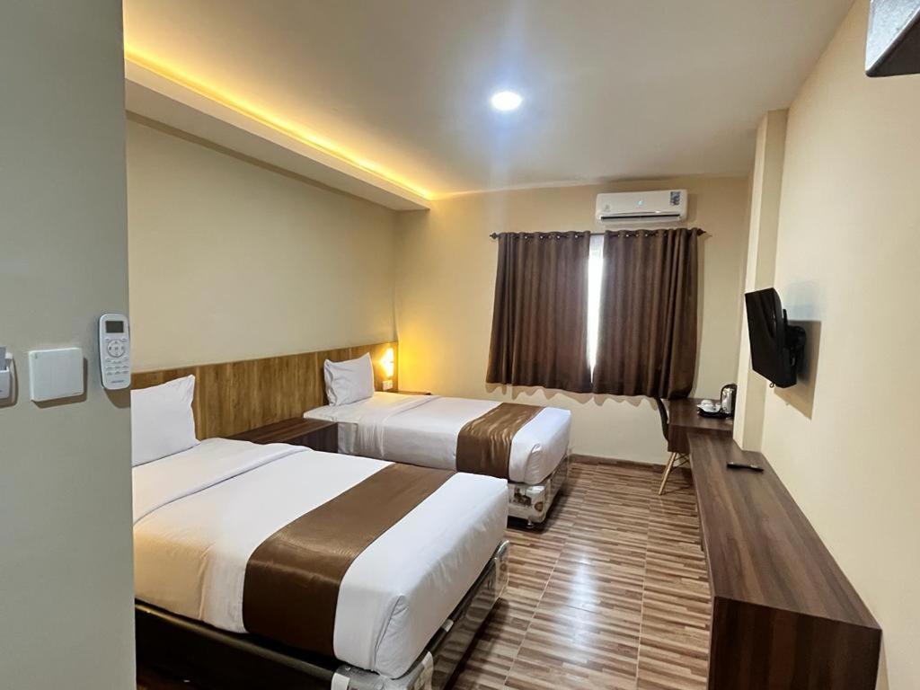 LubukpakamT HOTEL KUALANAMU的酒店客房设有两张床和电视。