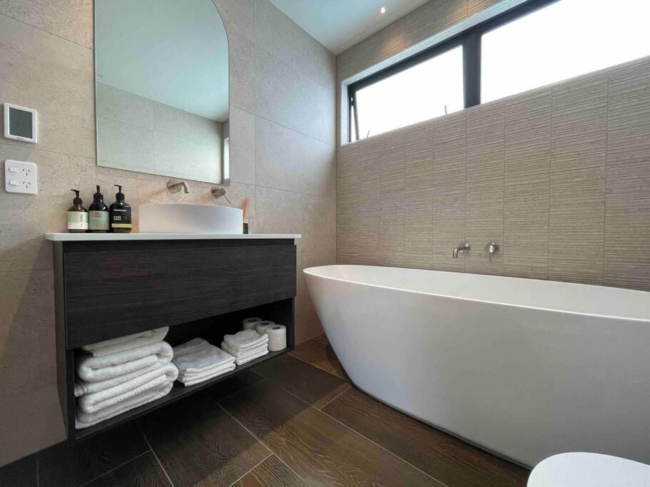 基督城Luxury 3 Bedroom Home With Double Garage的带浴缸、水槽和镜子的浴室