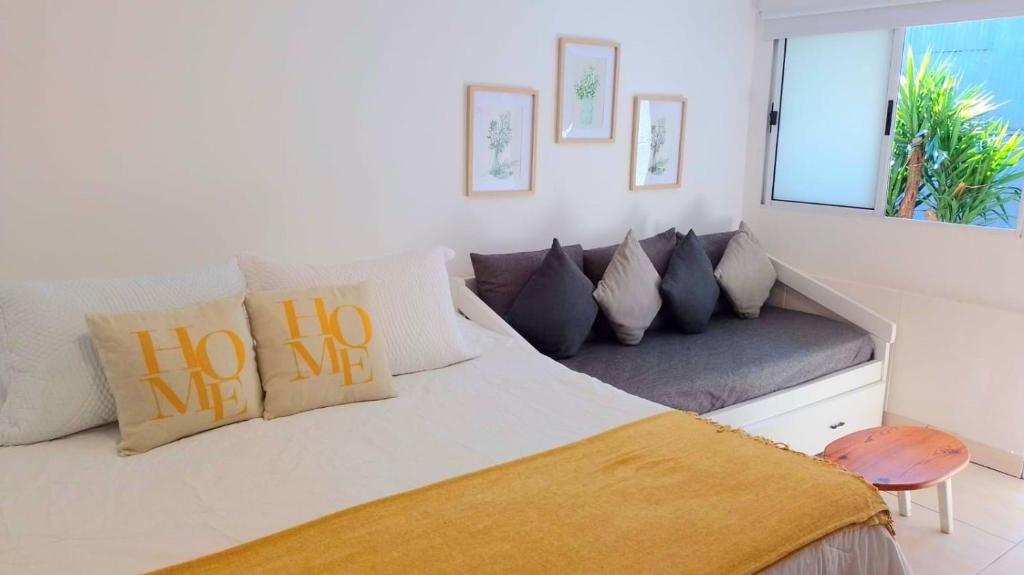 萨尔托Salto Chico Apart.的客房内的一张带枕头的白色床和一张沙发