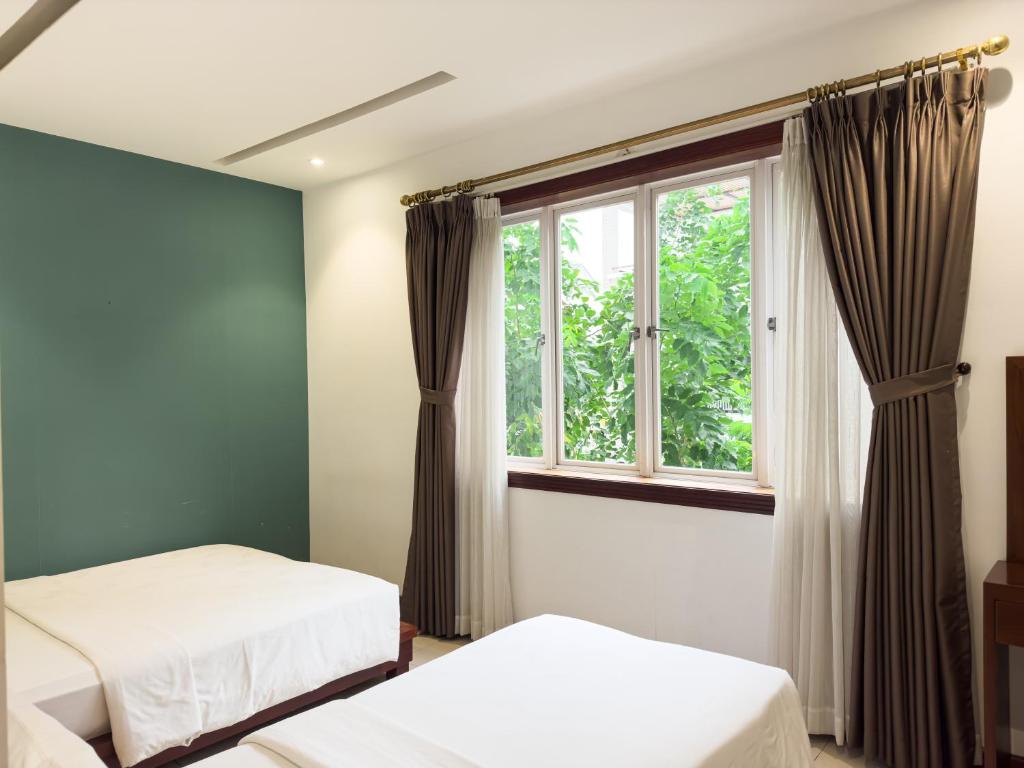 胡志明市Hoang Yen Hotel - Phu My Hung的一间卧室设有两张床和窗户。