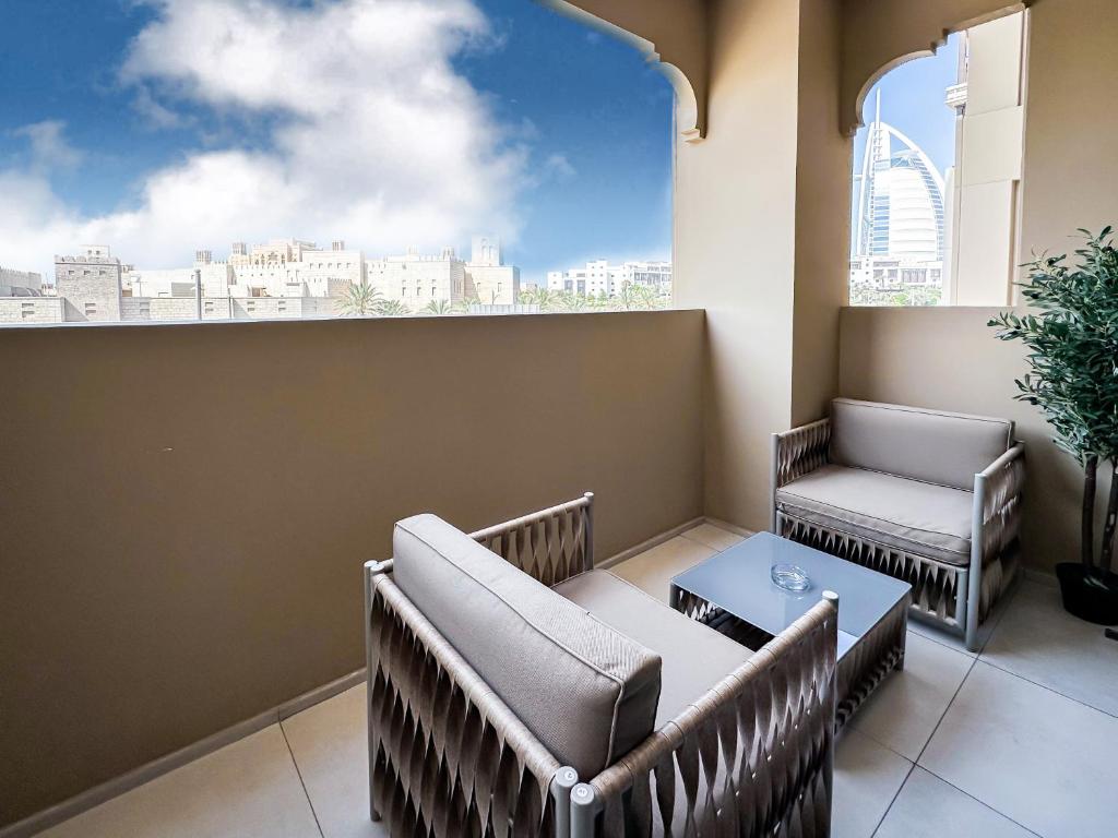 迪拜Trophy Luxe Jumeirah Retreat w Burj Al ARB views的阳台配有桌椅和窗户。
