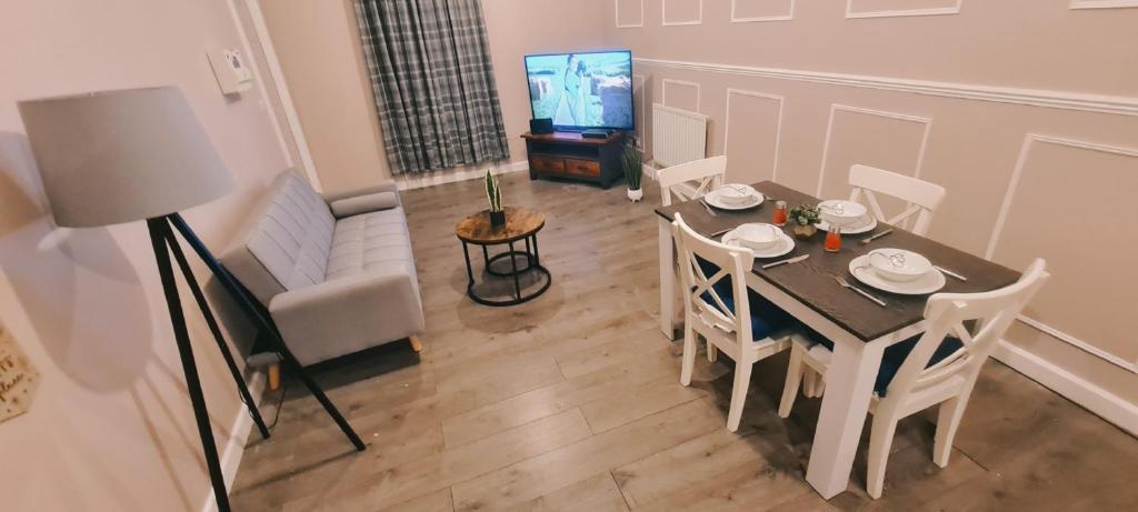 巴恩斯利Charming 1-Bed Apartment in Barnsley的客厅配有桌椅和电视。