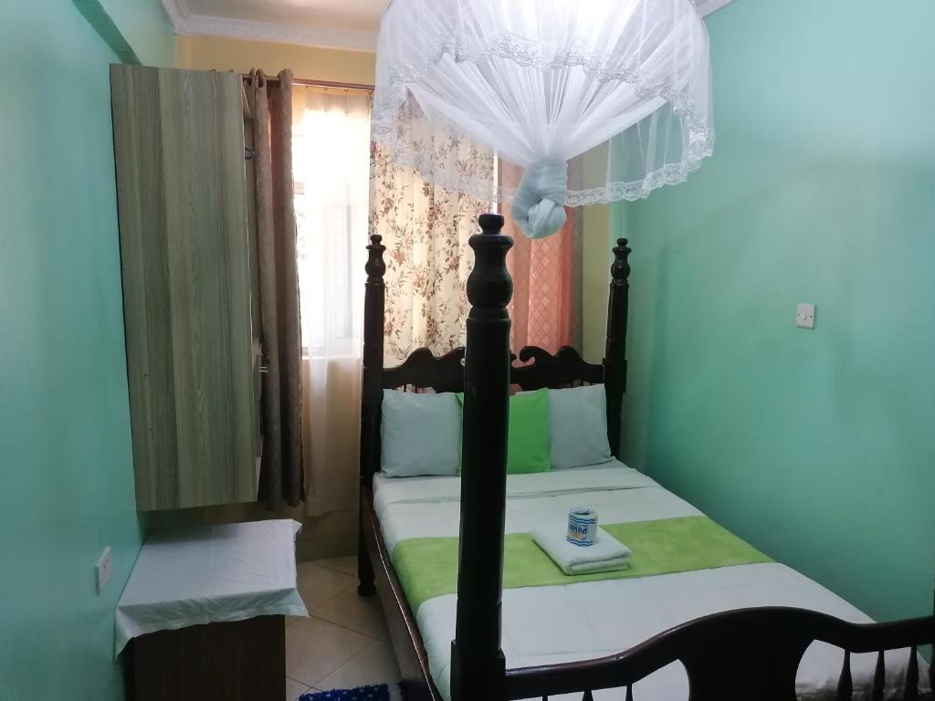 KakamegaMilimani Greens Inn的一间小卧室,配有一张带天蓬的床