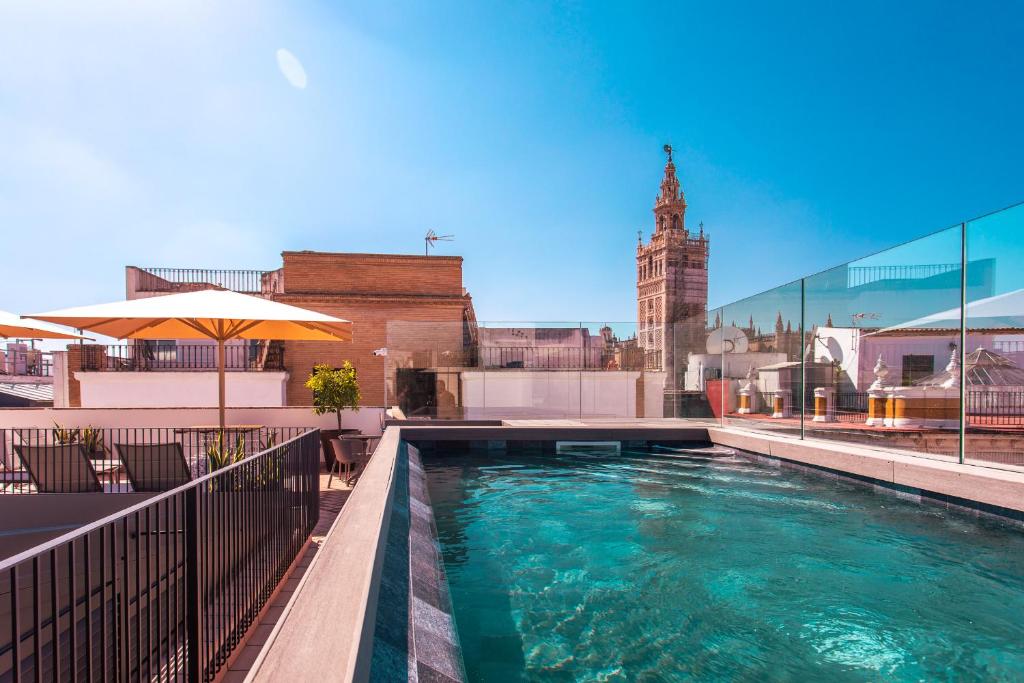 塞维利亚Casa Alhaja by Shiadu的一座带钟楼建筑顶部的游泳池