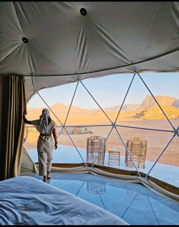 瓦迪拉姆Rum Goldeneye luxury camp的站在帐篷里,眺望沙漠的人
