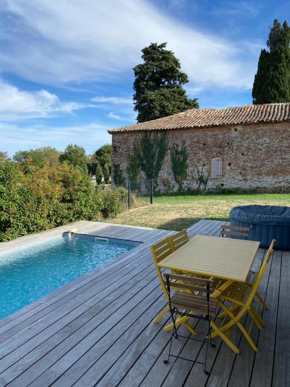 Saint-Jean-LhermMagnifique villa avec piscine et spa的游泳池旁的木甲板上配有桌椅