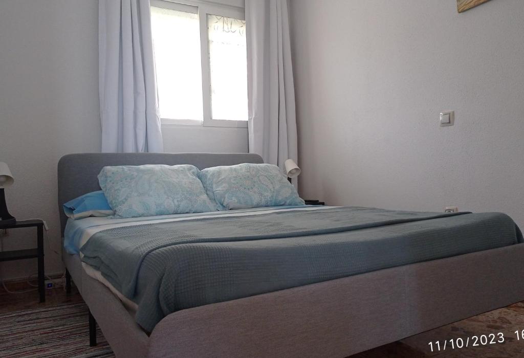 BustarviejoCasa de huéspedes Villa de las Hortensias的一间卧室配有一张带蓝色床单的床和一扇窗户。