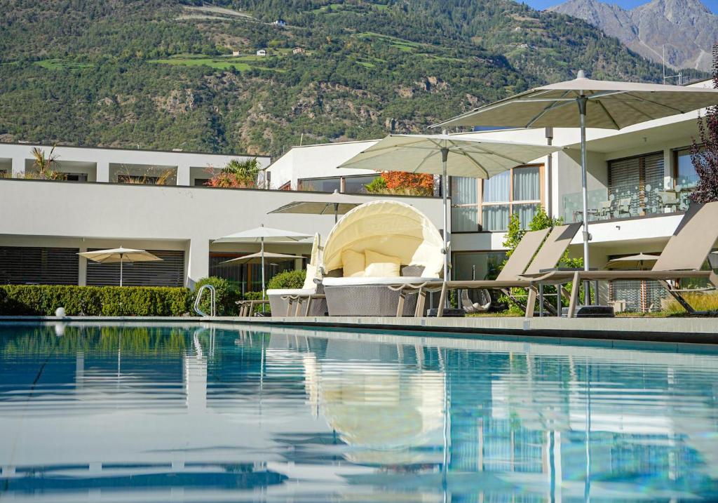 普劳斯Residence & Sportlodges Claudia的一个带椅子和遮阳伞的游泳池的度假酒店