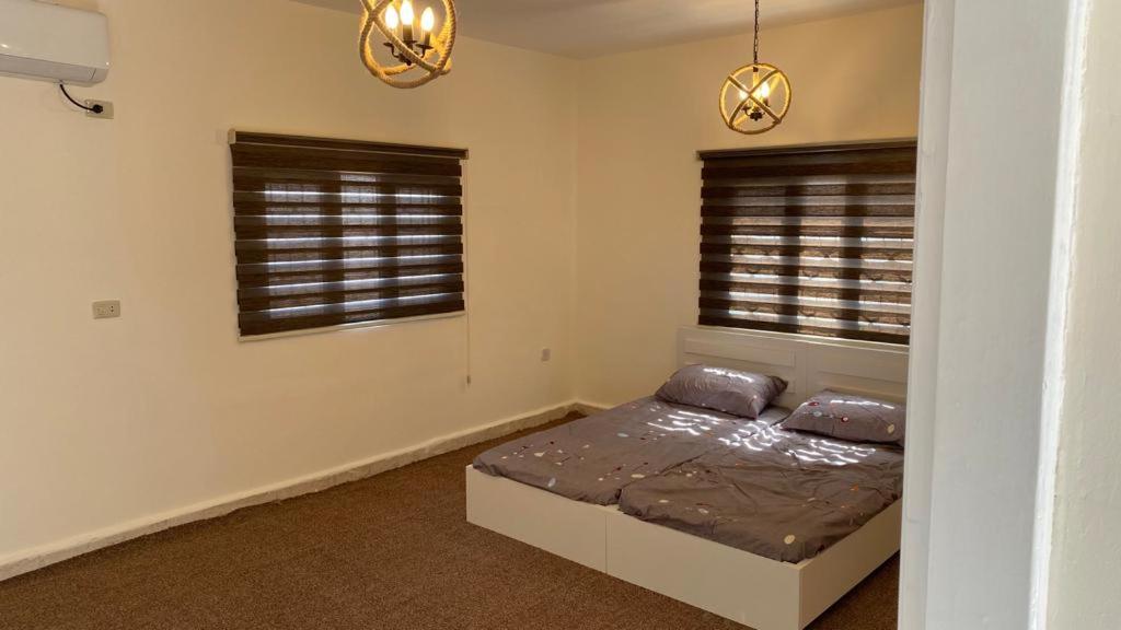 Al KhuraybahWadi Al-Nakhil Hostel的一间卧室设有一张床和两个窗户。